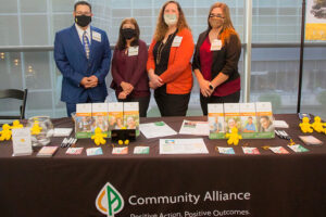 Community Alliance staff volunteers proudly showcasing an array of agency offerings during the reception. Photo Credit: A Better Exposure