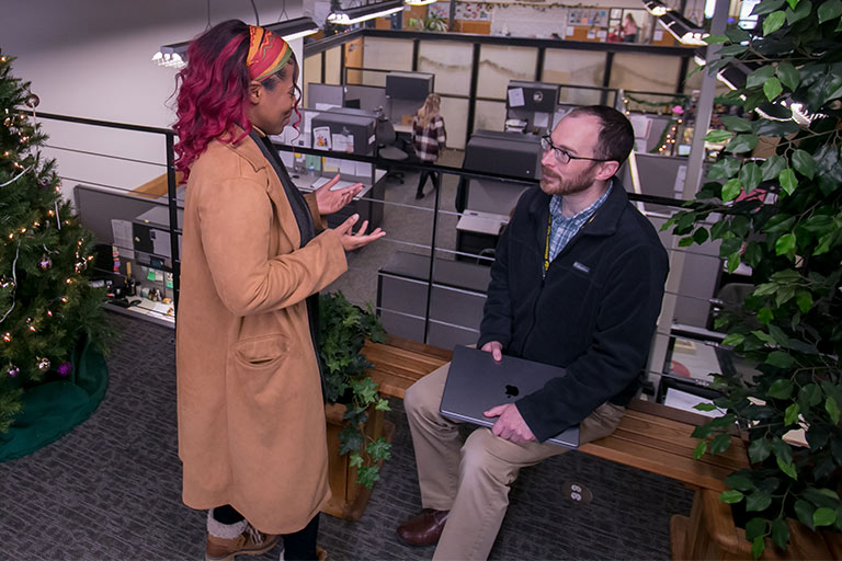 Young woman employee having conversation with another younger man employee