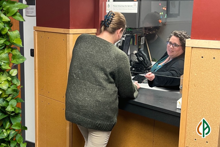 A person is greeted at a reception desk inside Community Alliance.