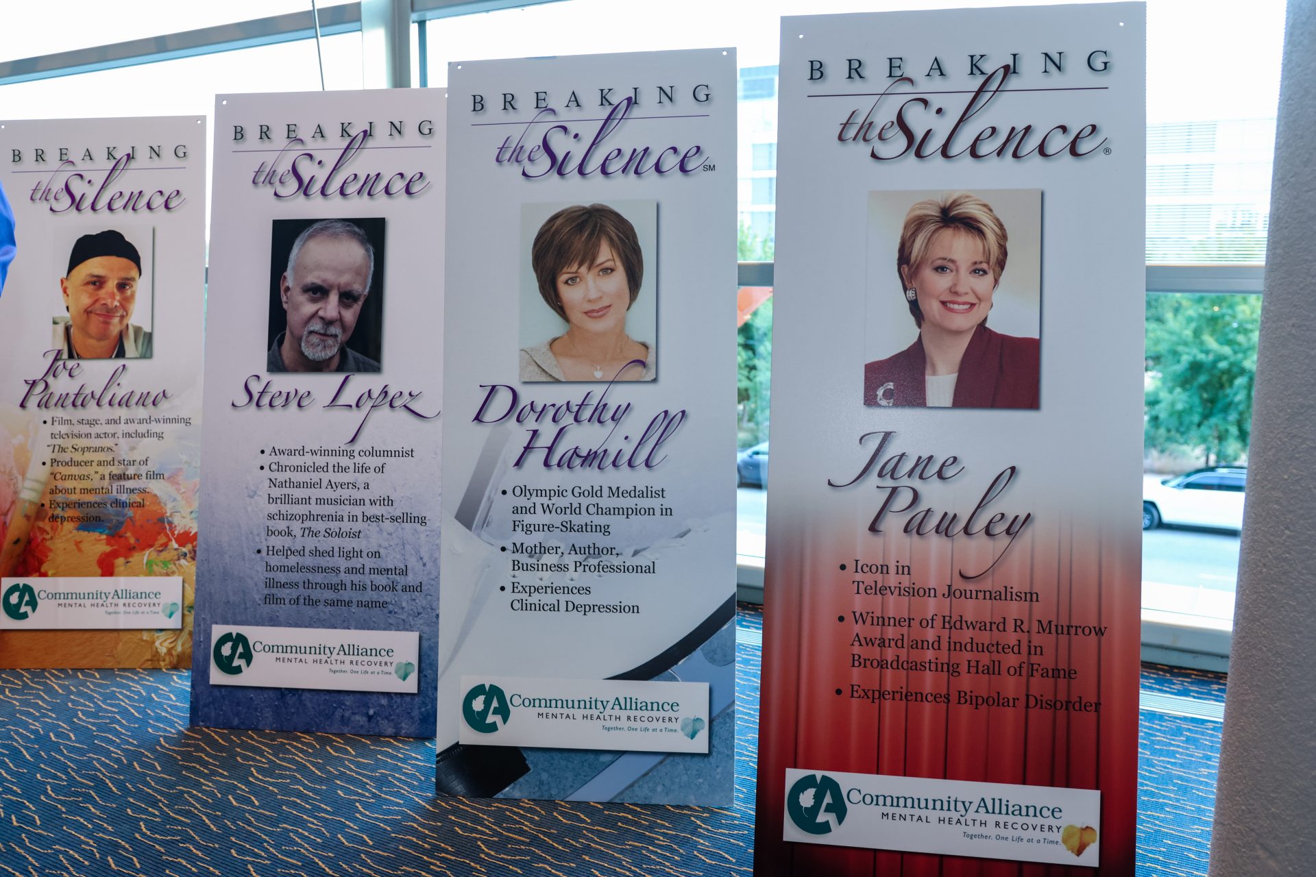 Four sponsor banners displayed inside the Holland Performing Arts Center in Omaha, positioned in front of tall windows. Banners include the names of Dorothy Hamill, Jane Pauley, Steve Lopez and Joe Pantoliano.
