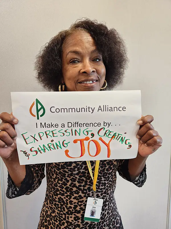 Community Alliance employee holding sign