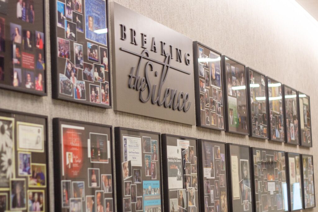 Shadow boxes featuring former Breaking the Silence speaker and memorabilia line a wall at Community Alliance 